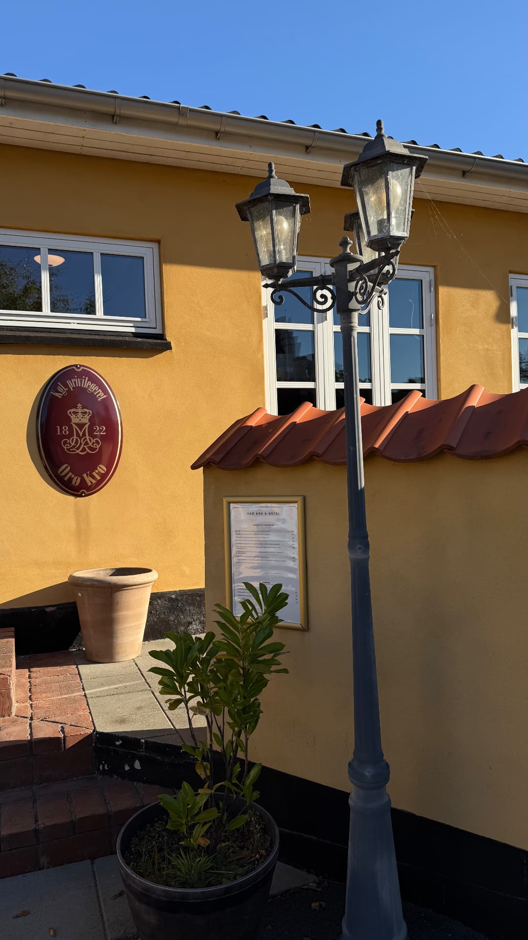 Kgl. privilegeret Orø Kro-skilt fra 1822 på den gule facade ved lygtepælen